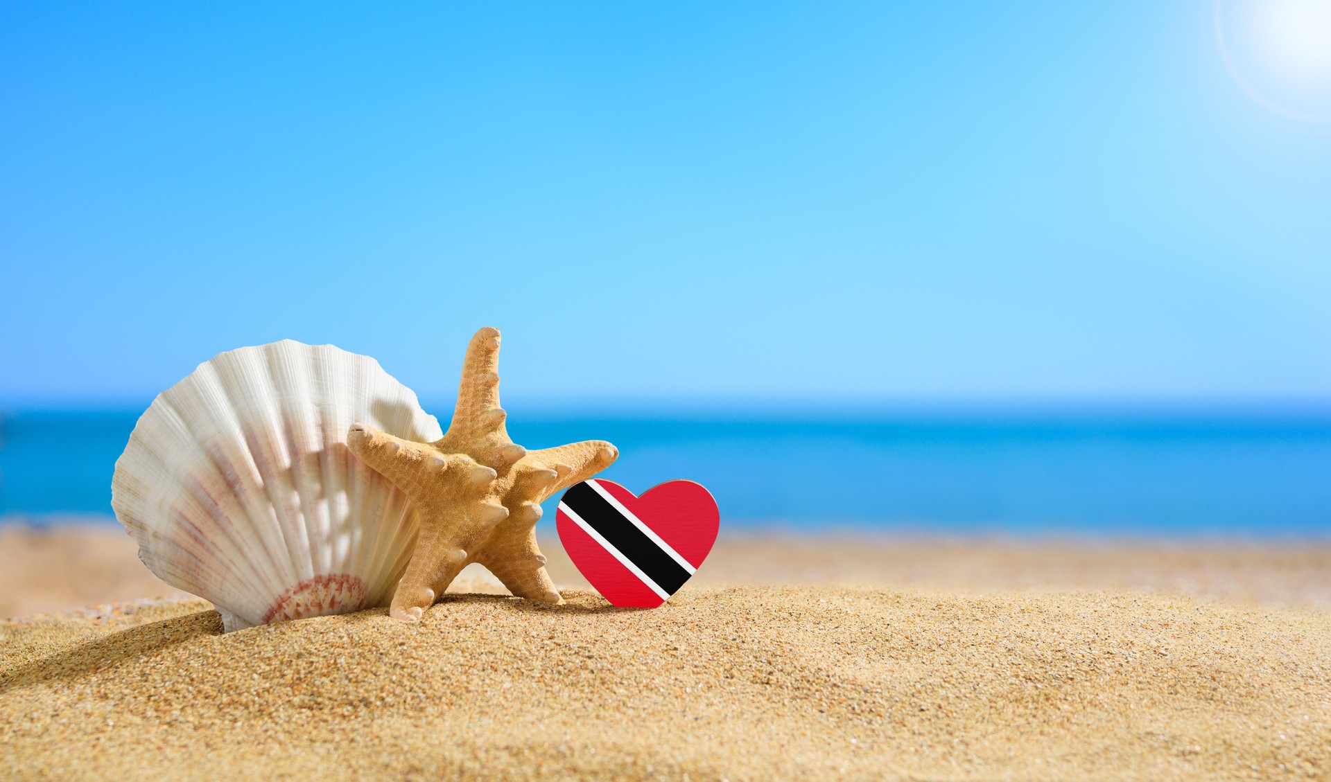Beautiful beach in the Trinidad and Tobago. Flag of Trinidad and Tobago in the shape of a heart and shells on a sandy beach.